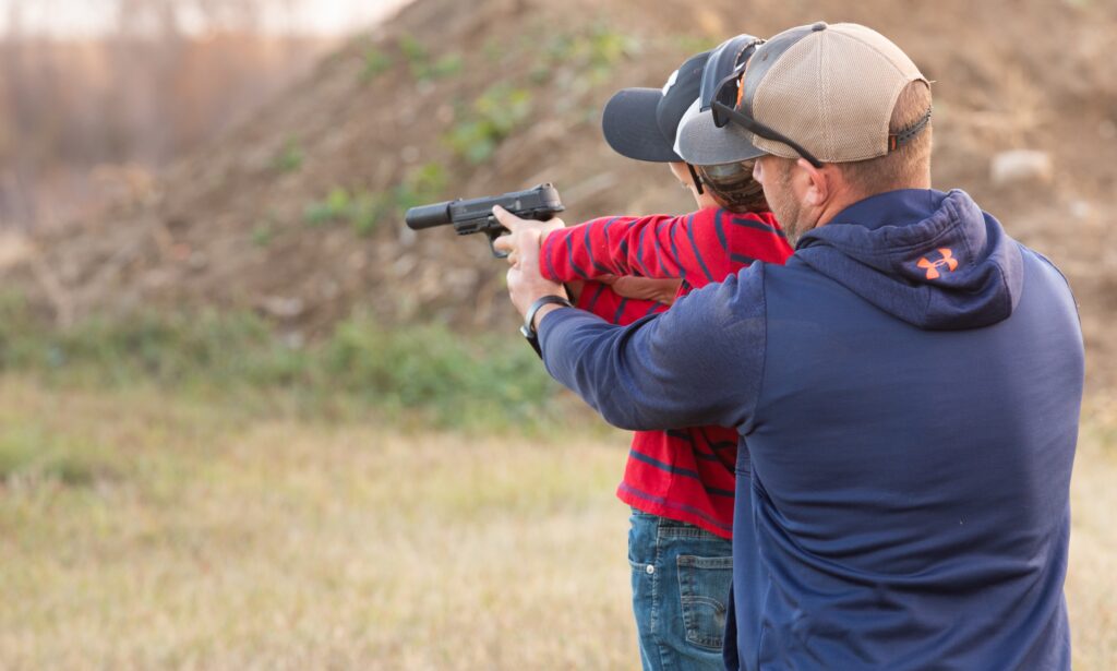 A kid shooting with a professional instructor in a Budapest shooting range.