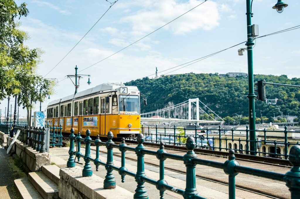 Iconic yellow tram in Budapest with scenic views of Gellért Hill and the Danube River, a picturesque highlight included in Budapest stag do packages.