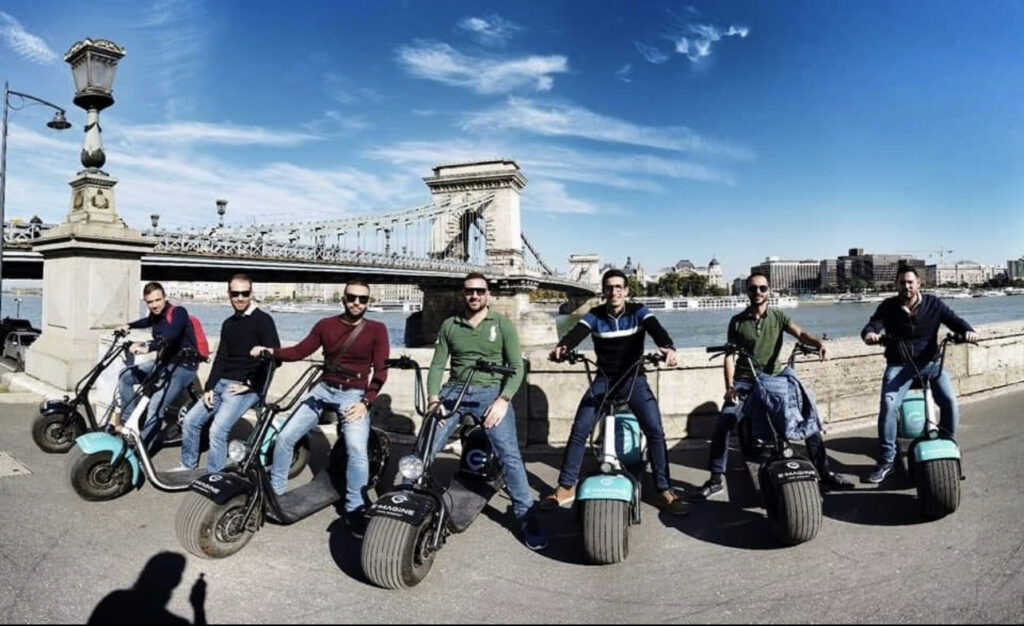 Group of friends on an e-bike tour along the Chain Bridge, part of a Budapest stag do itinerary.