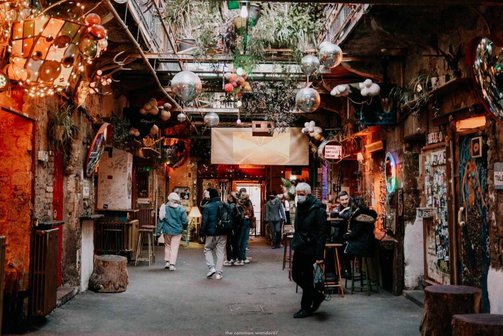 An eclectic indoor ruin bar in Budapest with a few visitors walking through its vibrant, rustic interior, showcasing the contrast between ruin bars vs rooftop bars.