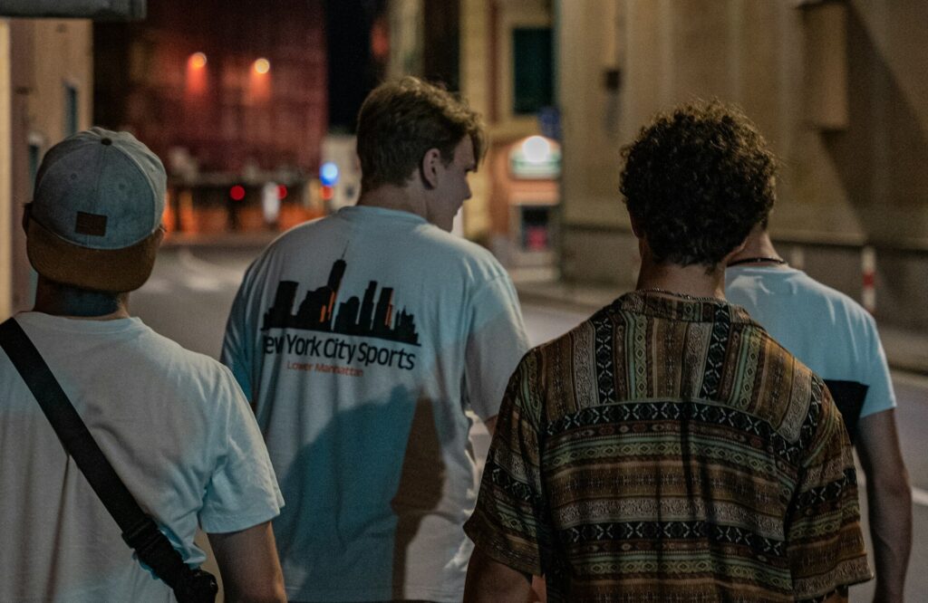 A group of friends walking through the streets of Budapest at night, heading towards a pub crawl. Perfect for a Budapest stag party, they are dressed casually, exploring the city's nightlife.