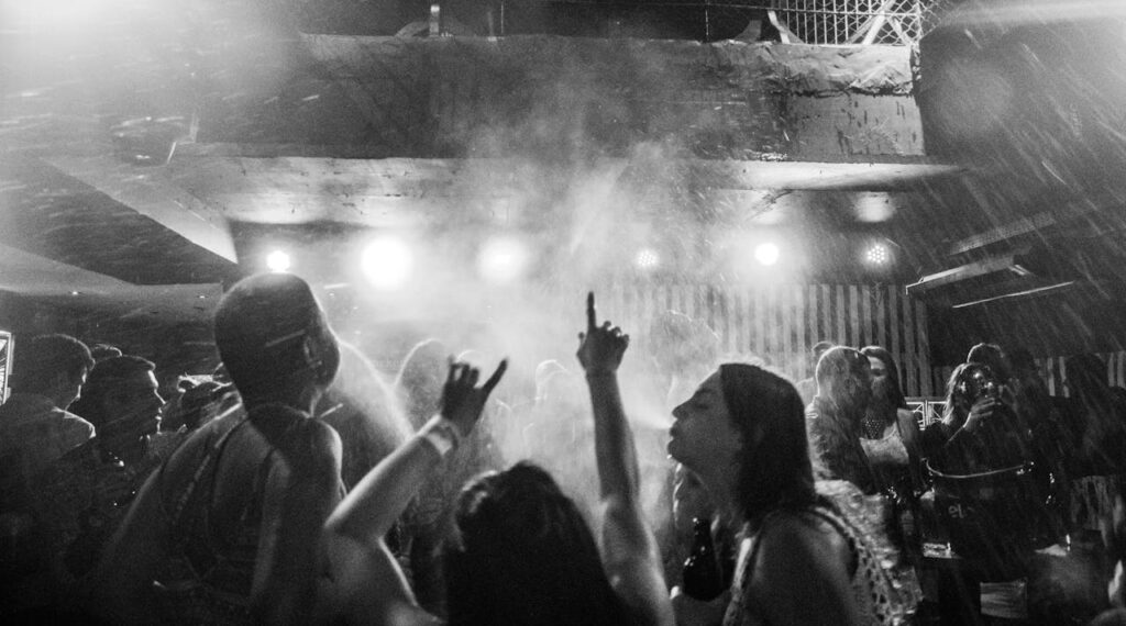 Group of people dancing and enjoying the party under colorful lights in a nightclub, capturing the vibrant atmosphere ideal for a Budapest stag do celebration.