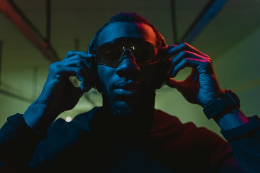 Man adjusting his protective gear, wearing ear protection and safety goggles at an indoor shooting range.