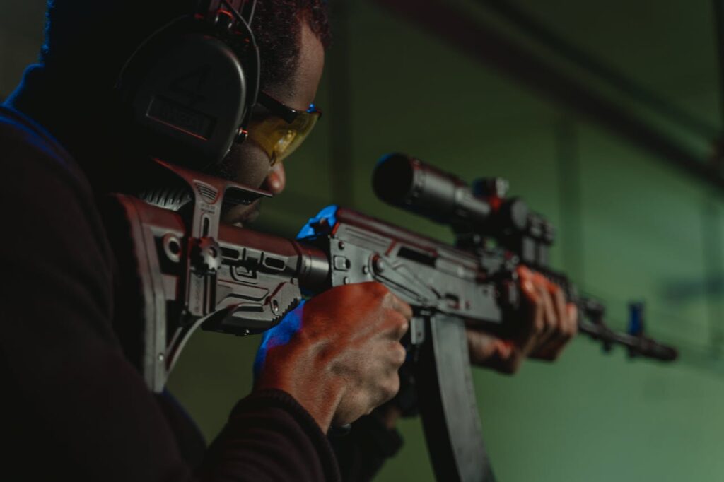 Man aiming a rifle during a gun shooting Budapest stag event, wearing protective ear and eye gear.