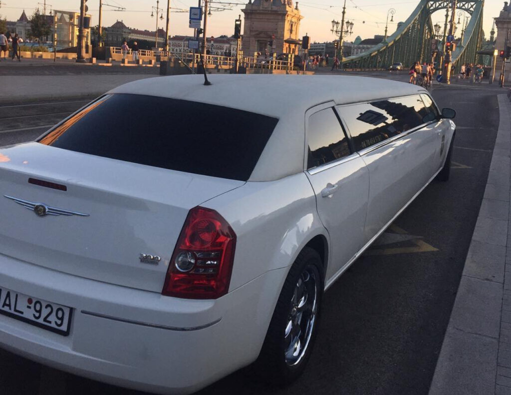 Chrysler limo for stag do transfer Budapest, parked near Liberty Bridge, offering luxury and comfort for unforgettable group travel.