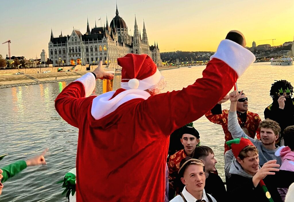 Festive celebration during a Private Riverboat Party on the Danube in Budapest, featuring costumed fun with the Parliament in the background.