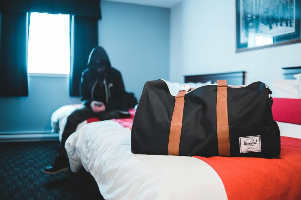 A duffel bag on a hotel bed with a person sitting in the background, representing accommodation planning for stag groups in Budapest.