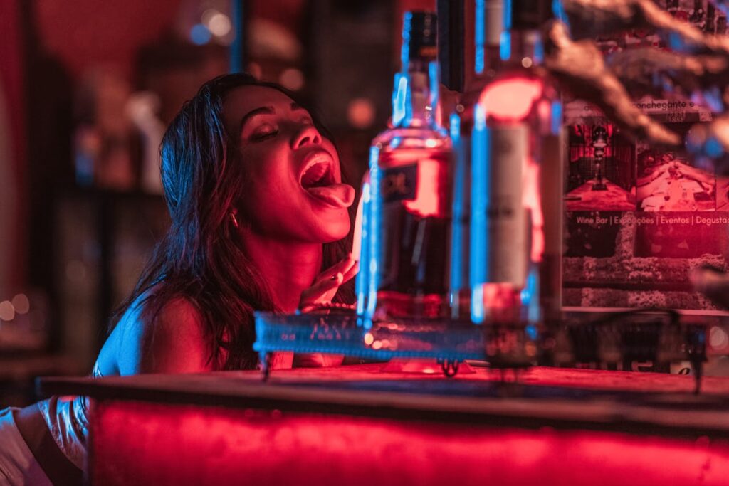 Woman enjoying the vibrant nightlife scene in Budapest, surrounded by neon lights and bottles, capturing the energetic atmosphere perfect for bachelor parties.