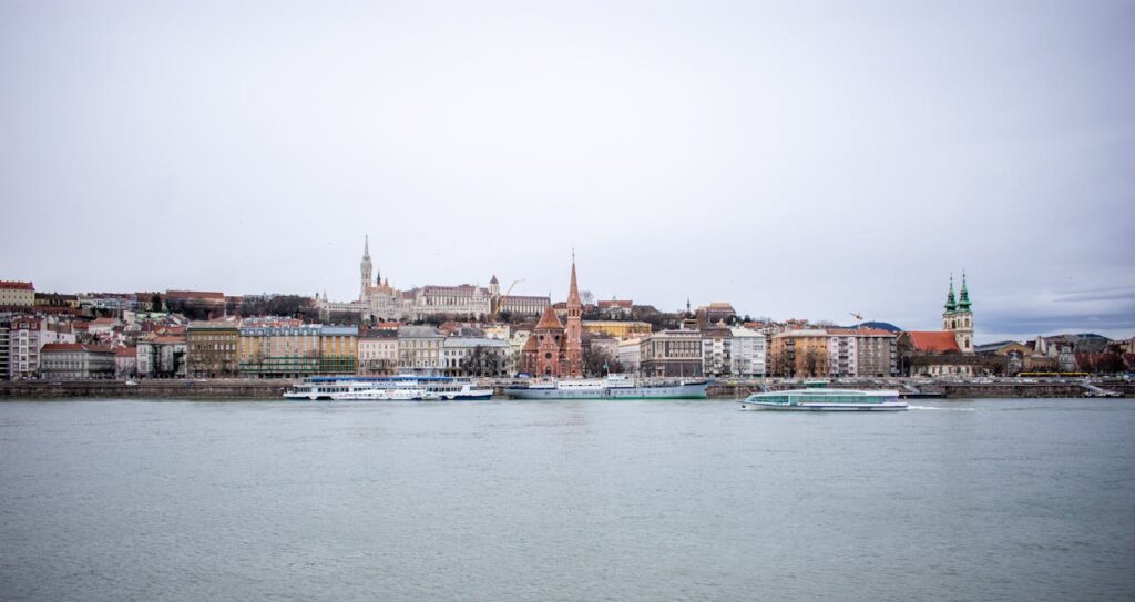 Danube River stag party with a scenic view of Budapest, boats cruising the river, historic buildings, and church spires lining the skyline.