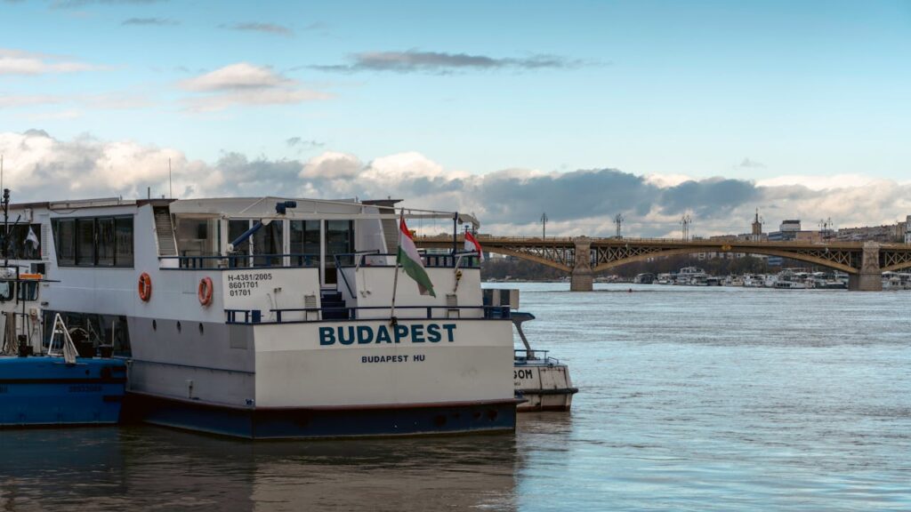 A riverboat docked on the Danube in Budapest, perfect for a Budapest things to do stag experience, with Margit Bridge in the background.