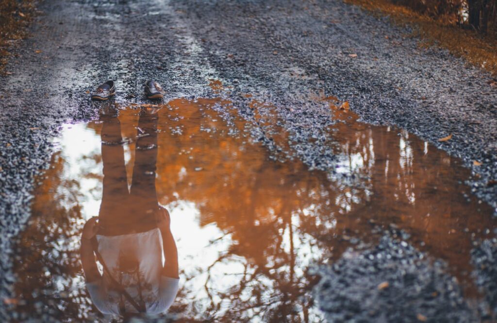 Reflection of a person in a muddy puddle, symbolizing the disappointment of Budapest stag do mud wrestling activities 