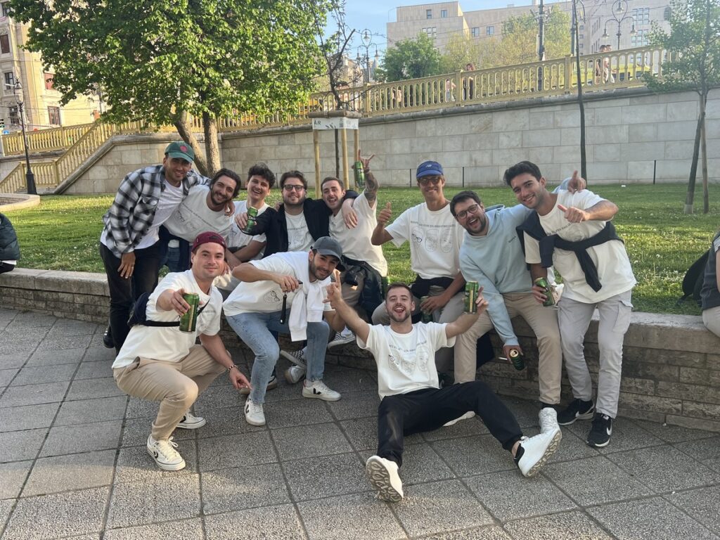 A group of friends celebrating outdoors, enjoying drinks and laughter on a sunny day.