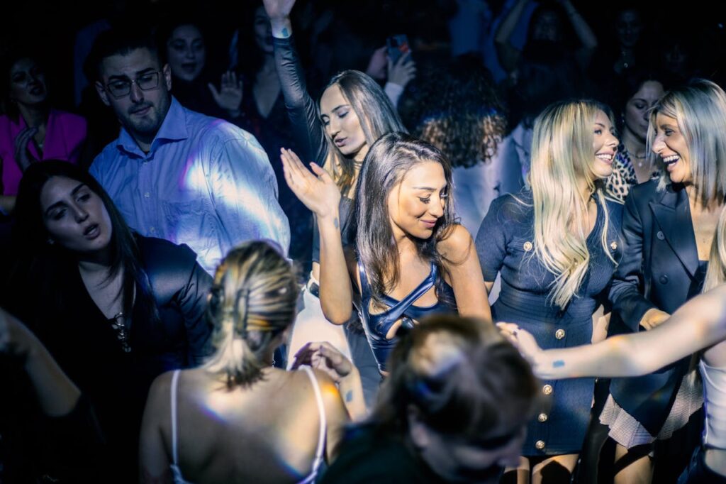 A lively group of friends enjoying the night and dancing at one of the best nightclubs in Budapest, illuminated by vibrant lights.