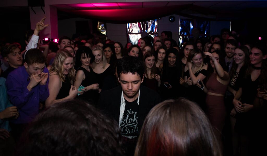 A vibrant crowd gathers around a young man dancing in one of the best nightclubs in Budapest, enjoying the energetic party atmosphere.