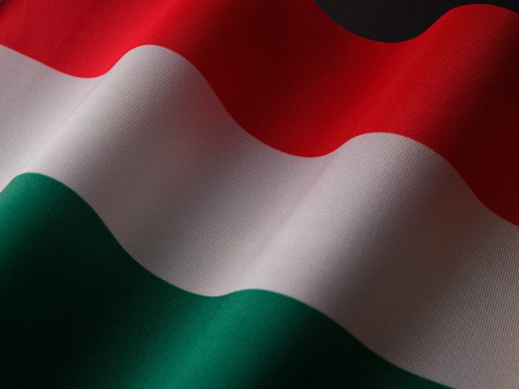 A close-up of the Hungarian flag made of textured fabric, displaying its red, white, and green horizontal stripes with gentle folds.